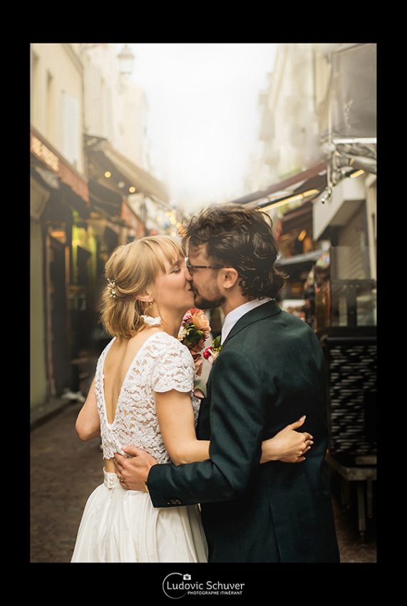 Photographe de mariage capturant un baiser spontané des mariés dans un environnement urbain